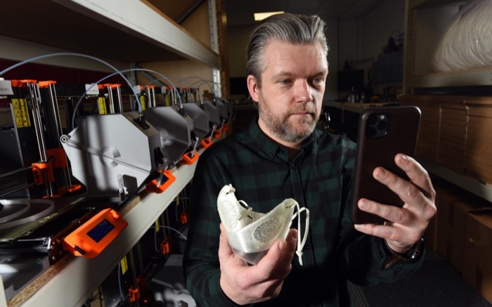 Steve holding a custom-fit mask beside the ActiveCell automated 3D print farm